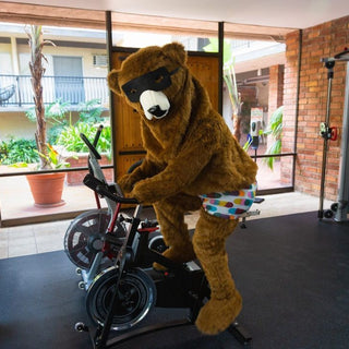 Social media post: Our Pair of Thieves Bear wearing SuperSoft boxer briefs at a gym riding a bike. 