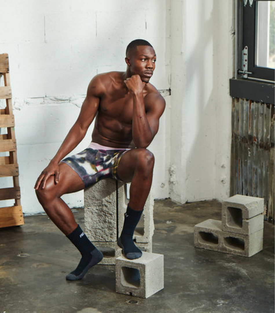 Individual wearing a pattern Hustle Boxer Briefs sitting on a pile of cinder blocks. This individual also has on some of our newest Hustle Crew Socks.  